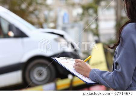 Insurance agent fills out paperwork after accident. Insurance agent fills out paperwork after accident. 67714673