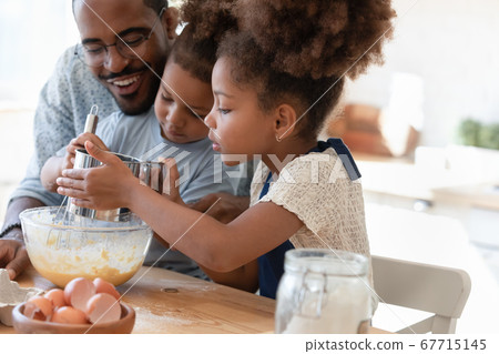 Happy biracial dad and little kids make dough for pastries 67715145