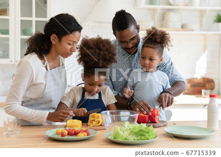 Loving biracial parents cooks in kitchen with small kids 67715339