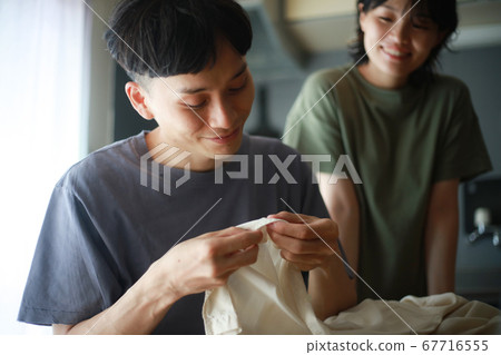 Men putting buttons on clothes Men putting buttons on clothes 67716555