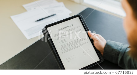 Businessman signing loan contract on tablet. 67716852