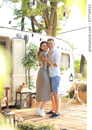 Young wife hugging husband near house on wheels. 67716932