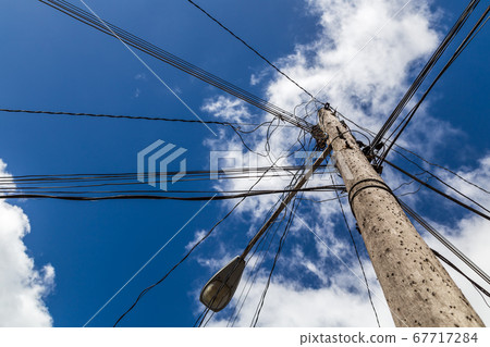 Looking up at a chaotic telegraph pole 67717284