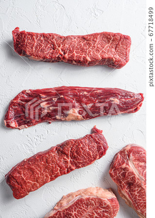 Raw organic machete steak near denver and top blade marble beef on white background top view close up. Raw organic machete steak near denver and top blade marble beef on white background top view close up. 67718499