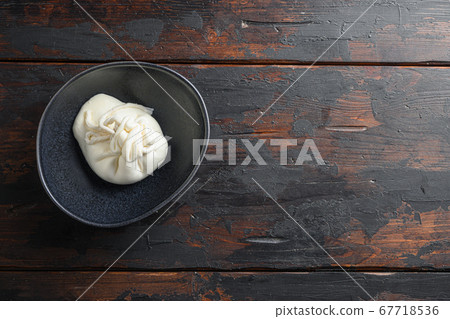 Creamy Italian Burrata Cheese in black plate over old wooden table< space for text horizontal Creamy Italian Burrata Cheese in black plate over old wooden table< space for text horizontal 67718536