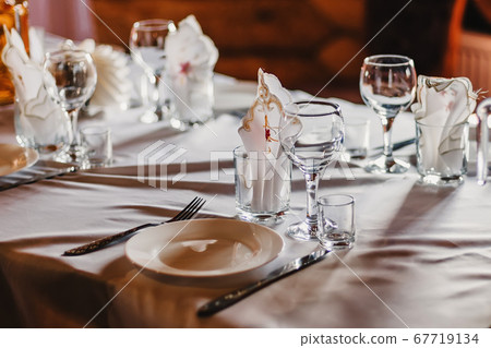 set of empty glasses and plates with Cutlery on a white tablecloth on the table in the restaurant set of empty glasses and plates with Cutlery on a white tablecloth on the table in the restaurant 67719134