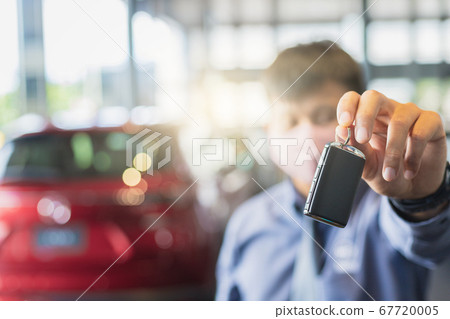 Asian man blurred holding in key car in dealership 67720005