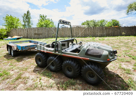 eight-wheeled all-terrain vehicle with a trailer on a meadow on a summer day 67720409