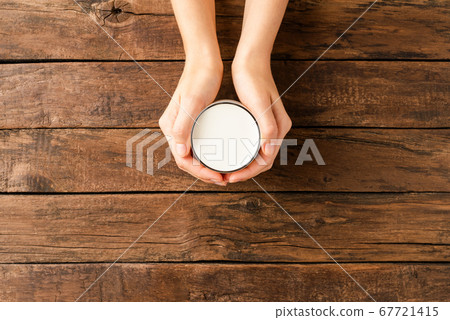 Overhead shot of female hands holding glass of milk on rustic wooden table with copyspace 67721415