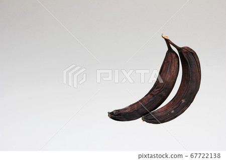 Spoiled old bananas. Two rotten blackened and  dried bananas . Spoiled food.  67722138