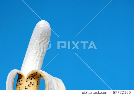 An open overripe banana is isolated on a blue background. 67722190