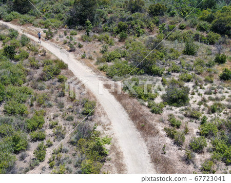 Aerial view of running man in a small singletrack trail in the valley 67723041