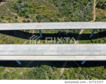 Aerial view of road highway bridge, viaduct supports in the valley among the green hills. 67723557
