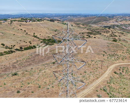 Aerial view of electricity transmission pylon in dry valley landscape 67723614