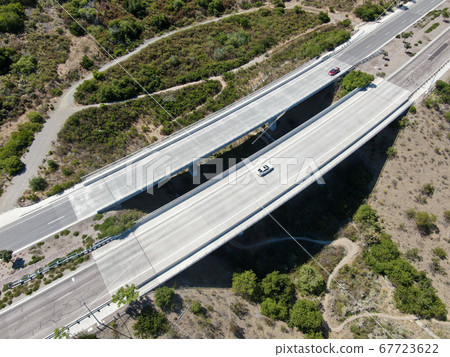 Aerial view of road bridge, viaduct supports in the valley among the dry yelllow hills Aerial view of road bridge, viaduct supports in the valley among the dry yelllow hills 67723622