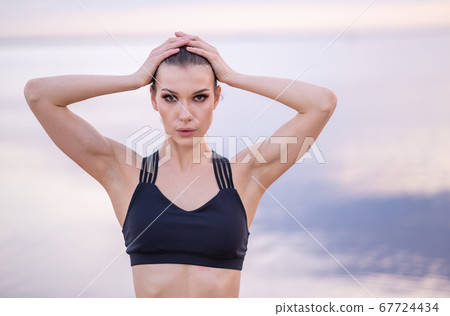 portrait of a beautiful fitness model on a background of the sea at sunset portrait of a beautiful fitness model on a background of the sea at sunset 67724434