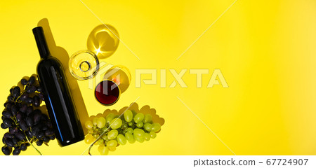 Two glasses of red and white wine, a bottle, grapes on a yellow background. The concept of Italian Two glasses of red and white wine, a bottle, grapes on a yellow background. The concept of Italian 67724907