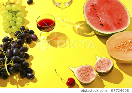 Two glasses of red and white wine. A woman pours wine from a bottle. Grapes and other fruits on a Two glasses of red and white wine. A woman pours wine from a bottle. Grapes and other fruits on a 67724908