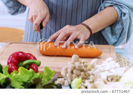 Close-up hand of woman wear apron sliced carrots 67731467
