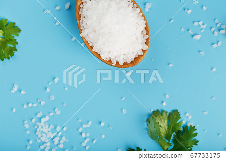 Large white sea salt in a wooden spoon on a blue 67733175