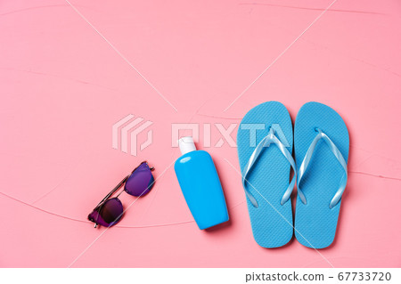 Blue flip-flops with sunscreen and sunglasses on pink background 67733720