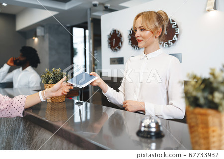 Hotel receptionist woman takes guest's passport for check in 67733932
