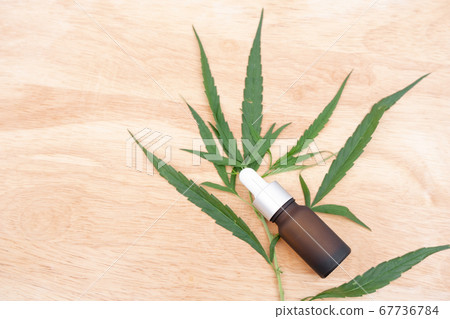 Glass bottle with extracting CBD oil formula and hemp leaf on a wooden floor. Medical cannabis concept 67736784
