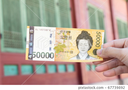 Traveller hand hold 50000 korean won banknote on defocused Korean palace background. Traveller hand hold 50000 korean won banknote on defocused Korean palace background. 67739892