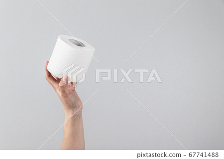 Female hand holds a soft roll of toilet paper on a gray background with copy space. Composition for advertising, article or banner Female hand holds a soft roll of toilet paper on a gray background with copy space. Composition for advertising, article or banner 67741488