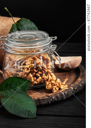 Walnut kernels in a glass bowl on a dark wooden background. Close-up. Walnut kernels in a glass bowl on a dark wooden background. Close-up. 67742667