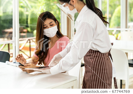 Asian waitress show menu with tablet. Asian waitress show menu with tablet. 67744769