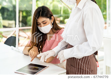 Asian waitress show menu with tablet. 67744770