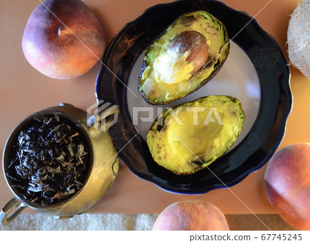 two avocado halves on a plate, three ripe peaches two avocado halves on a plate, three ripe peaches 67745245