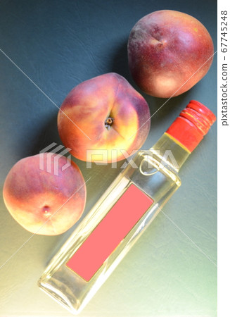 three ripe peaches close-up over a bottle with a three ripe peaches close-up over a bottle with a 67745248
