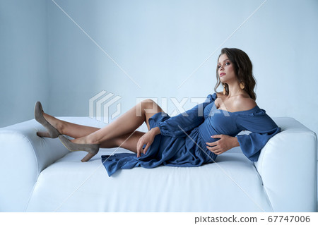 Sexy female model in midi dress on couch. 67747006