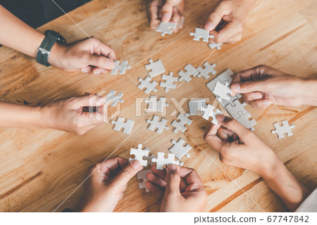 Business team handle a piece of white puzzles that Business team handle a piece of white puzzles that 67747842