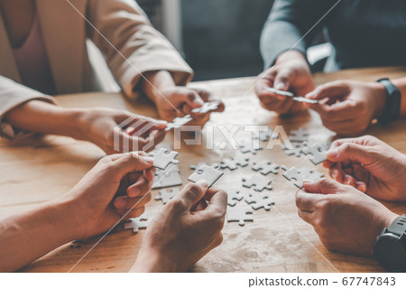 Business team handle a piece of white puzzles that Business team handle a piece of white puzzles that 67747843