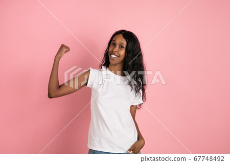 Cheerful african-american young woman isolated on pink background, emotional and expressive 67748492