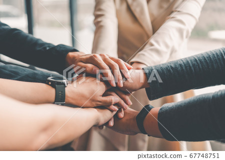 Hands of business people come together in a stack Hands of business people come together in a stack 67748751
