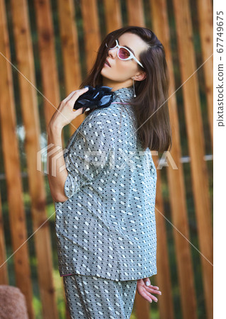 Young woman in pajamas is standing on wooden terrace in tropical country and look on jungle 67749675