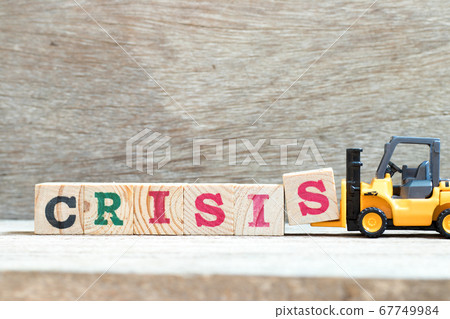 Toy forklift hold letter block s to complete word crisis on wood background Toy forklift hold letter block s to complete word crisis on wood background 67749984