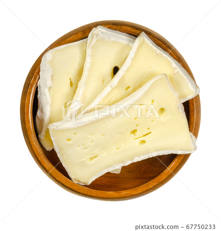Slices of soft mould cheese in wooden bowl. Moist creamy cheese, made of cow milk, ripened on the surface with a special fungus. Well known as Camembert or Brie. Closeup, from above, macro food photo. 67750233