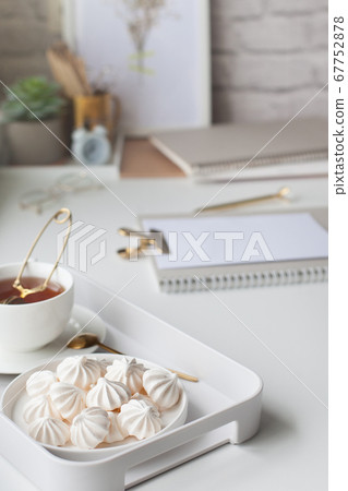 Work table near the window in the Scandinavian Nordic style. Female work and home office concept. White and gold office. Flowers in a vase and rings, bracelets on the table. Work table near the window in the Scandinavian Nordic style. Female work and home office concept. White and gold office. Flowers in a vase and rings, bracelets on the table. 67752878