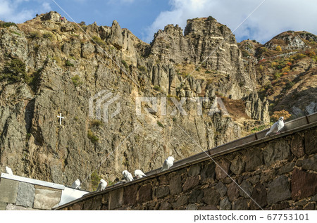 The roof with pigeons and a view of the mountains of Geghama ridge near Geghard monastery in Armenia The roof with pigeons and a view of the mountains of Geghama ridge near Geghard monastery in Armenia 67753101