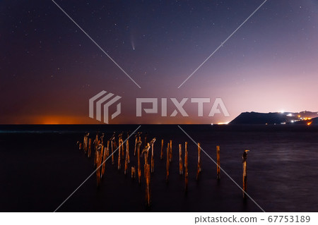 Comet C/2020 NEOWISE at night star sky with sea, birds and city lights 67753189