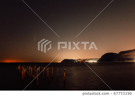 Comet C/2020 NEOWISE at night star sky with sea, birds and city lights 67753190