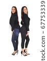 Two lovely woman standing back to back and smiling 67753339