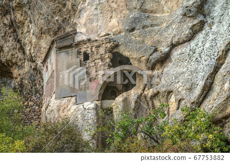 Preserved corner and arched entrance to the cave church in the rock near the territory of Geghard monastery of Armenia Preserved corner and arched entrance to the cave church in the rock near the territory of Geghard monastery of Armenia 67753882
