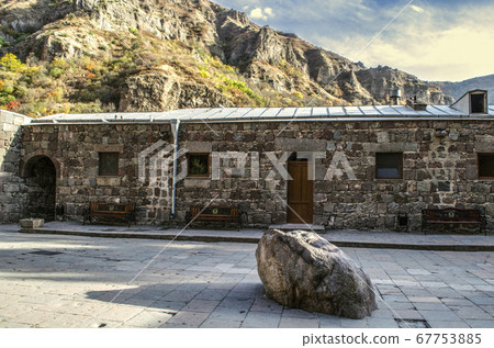 Geghard monastery in Armenia with a sacred stone in the courtyard and benches for pilgrims next to the room for priests Geghard monastery in Armenia with a sacred stone in the courtyard and benches for pilgrims next to the room for priests 67753885