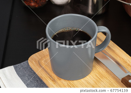 Cup of hot coffee on wooden board on kitchen table 67754139